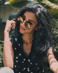 Young woman wearing sunglasses while sitting in park