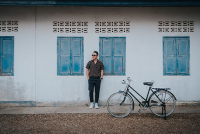 Full length of man standing by bicycle outside house