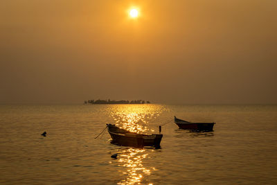 Boat in sea against sky during sunset