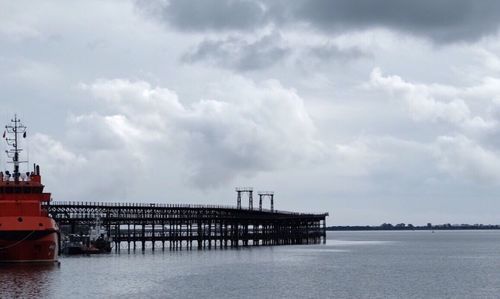 Pier on sea against cloudy sky