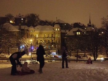 People walking on illuminated street during winter at night