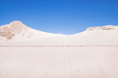 Scenic view of desert against clear blue sky