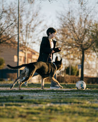 Selective focus in motion. kid playing football with dog in a park