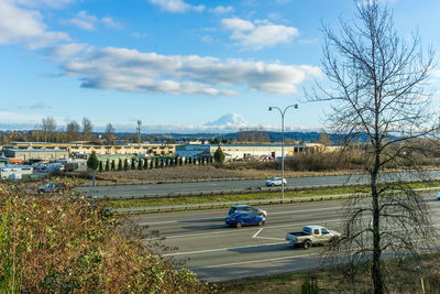 Cars on road by lake against sky