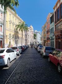 Cars on street amidst buildings in city against sky