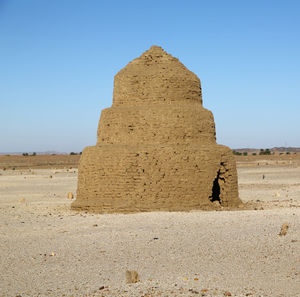 Stone wall on sand dune against clear sky