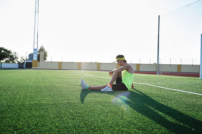 Young man practices stretching on the grass after his daily training