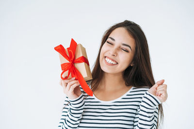 Portrait of young woman holding christmas tree against white background