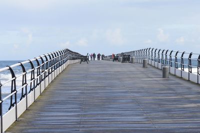 Footbridge over sea against sky