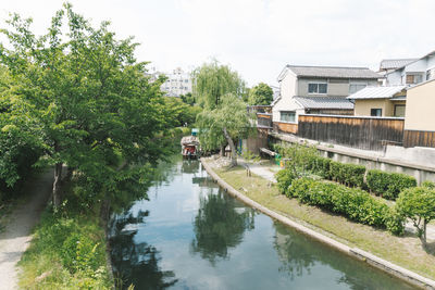 Canal amidst trees and buildings against sky