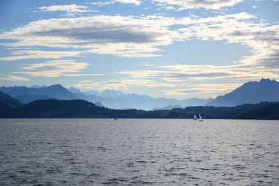 Scenic view of sea by mountains against sky