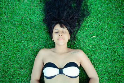 Directly above shot of woman with black hair lying on grass