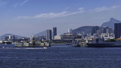 Sea by city buildings against sky