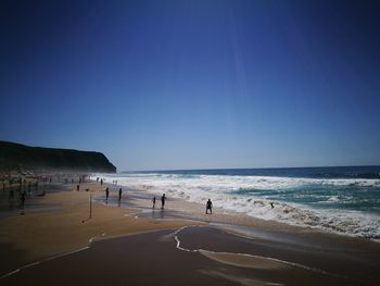 Scenic view of beach against clear blue sky