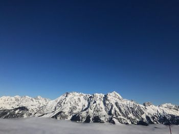 Scenic view of snow covered mountains against blue sky