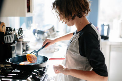 Teen girl flips a steaming hash brown in a cast iron pan