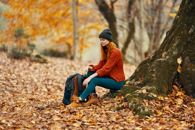 Young woman sitting on leaves during autumn