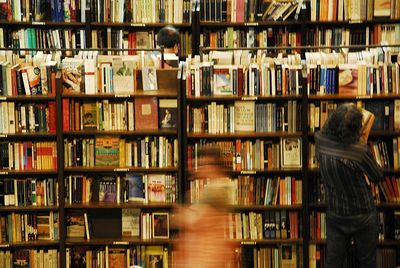 Rear view of man holding book in library