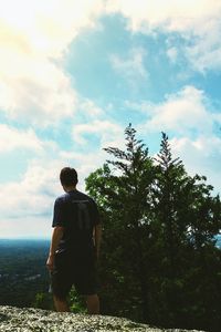 Rear view of man standing by tree against sky