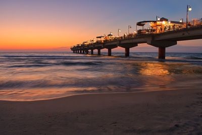 Pier over sea against sky during sunset