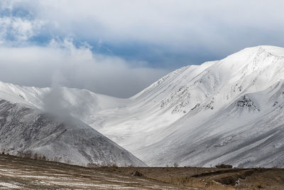 Scenic view of snowcapped mountains against cloudy sky