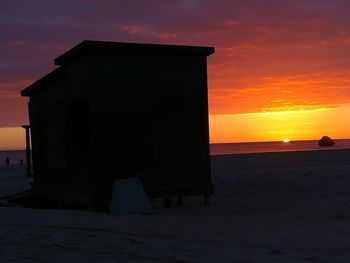 Silhouette beach against sky during sunset
