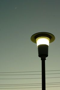 Low angle view of illuminated street light against wall