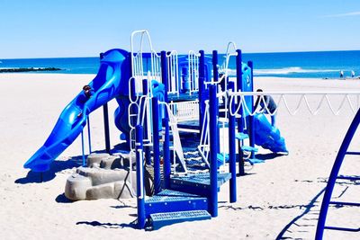 Deck chairs on beach against clear blue sky