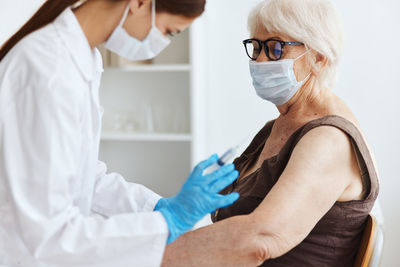 Doctor vaccinating senior woman at clinic