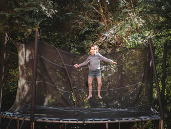 A beautiful caucasian girl in shorts and a sleeved t-shirt jumps on a trampoline