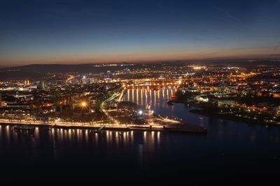 High angle view of illuminated buildings by river against sky at night