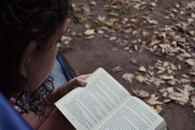 High angle view of woman reading book outdoors