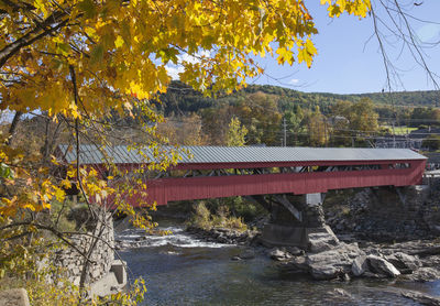 Bridge over river by trees against sky