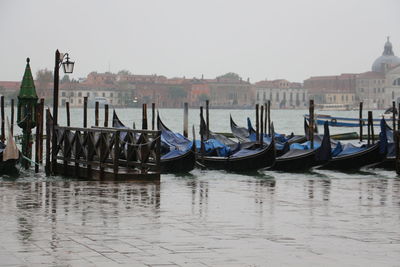 Boats moored in canal by city against clear sky