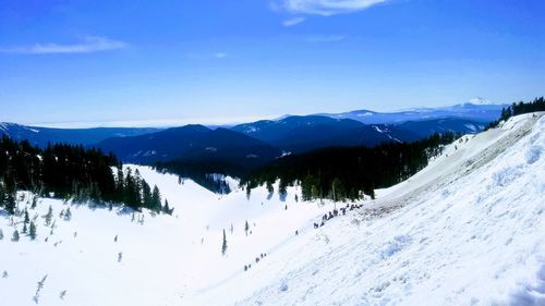 Scenic view of snow covered mountains against blue sky