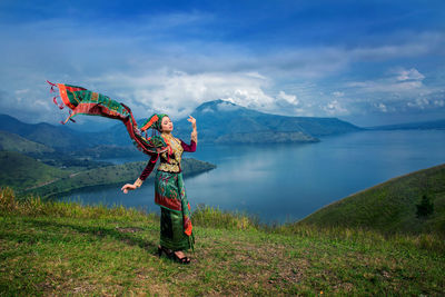 Woman wearing traditional clothing while standing on mountain against lake