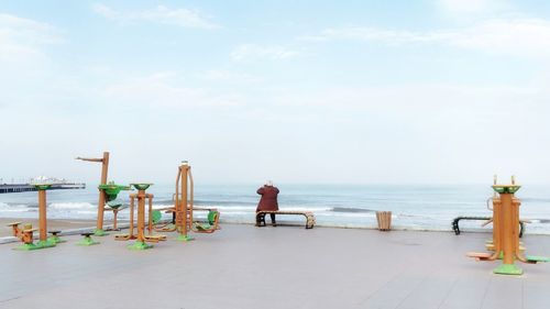 Rear view of man sitting on bench at promenade