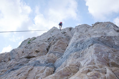 Low angle view of woman on rock against sky