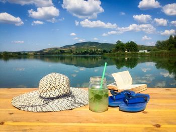 Lounge chairs and tables in lake against sky