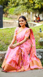 Young woman sitting on pink while looking away