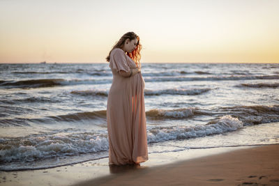 Young pregnant woman with a beautiful sea view on the background. happy and calm pregnant woman