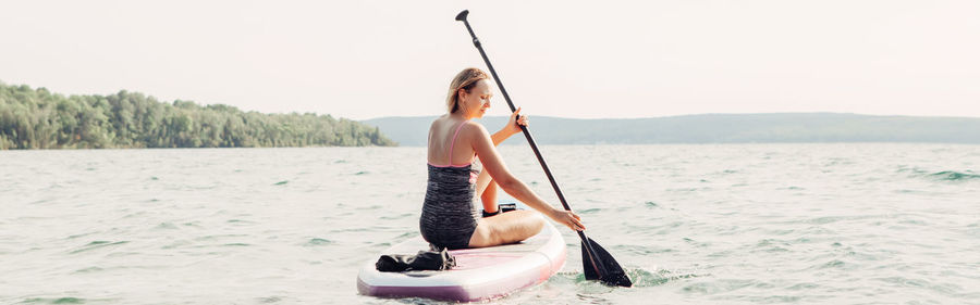 Woman on boat in sea against clear sky