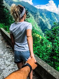 Rear view of woman with boyfriend on mountain against trees