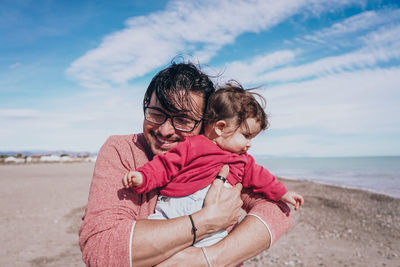 Full length of father with daughter on beach against sky