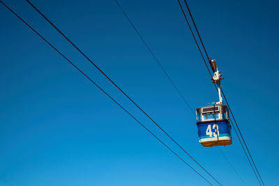 Low angle view of overhead cable car against blue sky