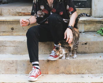 Low section of woman sitting with cat on steps