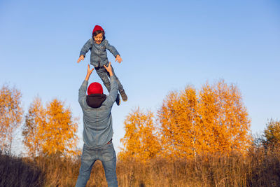 Portrait of a village boy child and father in red hats throws up into the sky