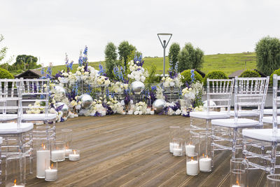 White flowers on table by chairs against sky