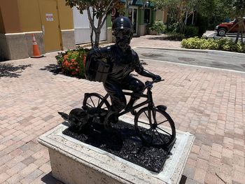 Statue on footpath by street in city