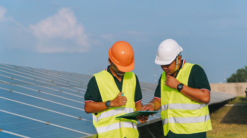 Rear view of man working with mobile phone against sky